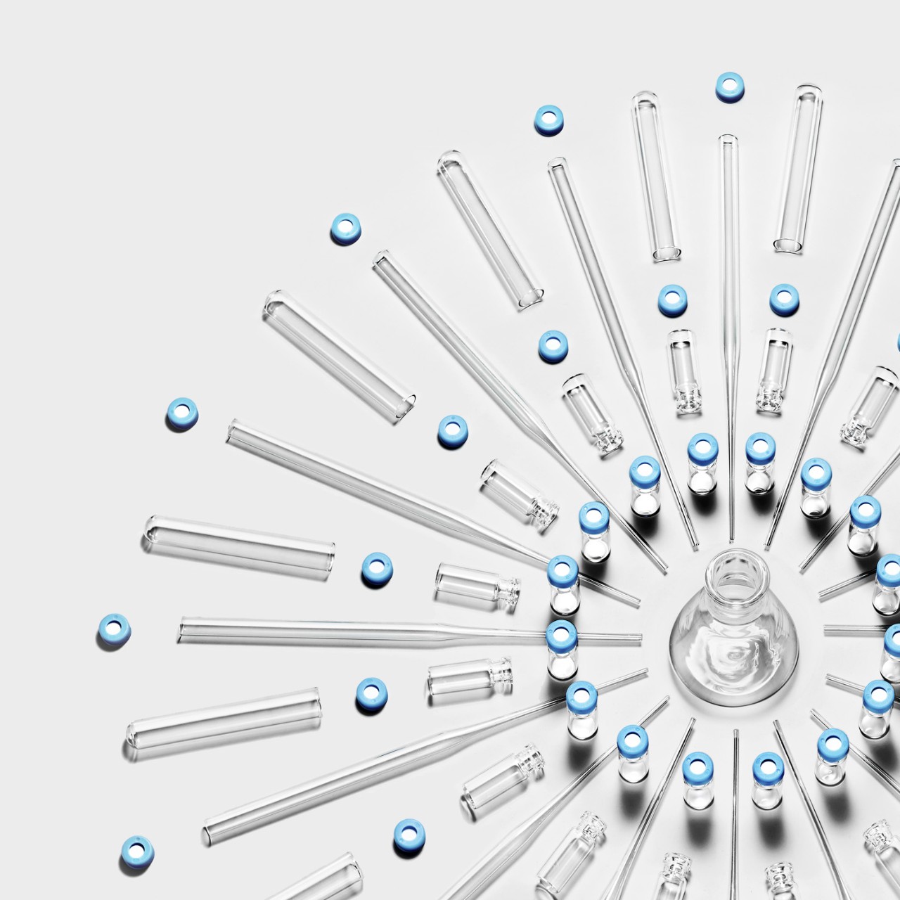 Droppers and test tubes arranged around a beaker in a pattern resembling a snowflake.